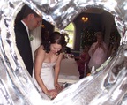 arty shot through ice sculpture of the bride cutting the cake