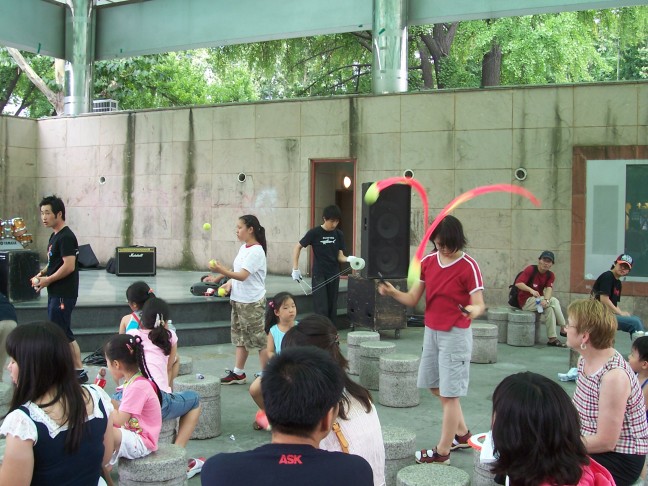 Susan watches jugglers practicing in the park.