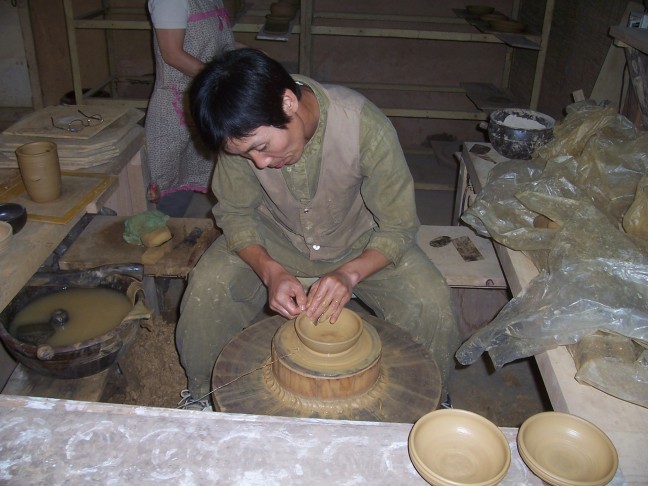 The potter smooths the edge of a bowl.