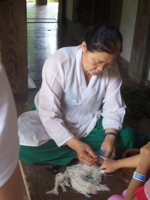 Applying nail polish. Crushed roses petals are applied and wrapped until dry.