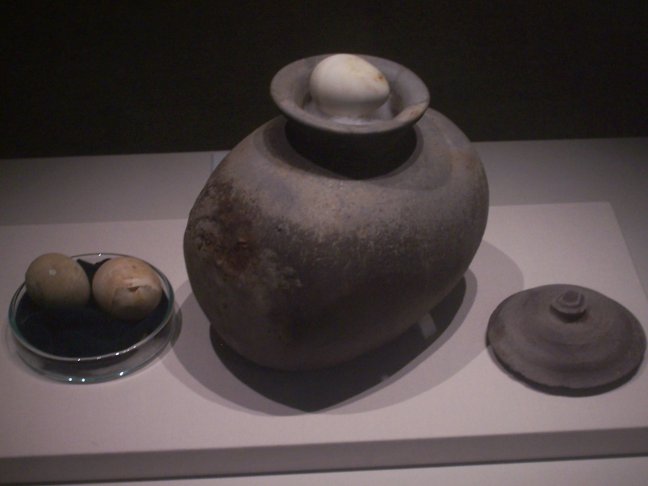 A caption tells us that these eggs in a horizontal jar were "in an iron cauldron at the bottom of funerary objects chest from Cheonmachong. ... In every tale about the establishment of Silla appears a hen or an egg. [This egg] represents both the birth of a new life and the resurrection."