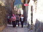  Ancient street between ancient walls still housing residents; a red-wrapped broom sticking out over a doorway means beer is available; Ollantaytambo