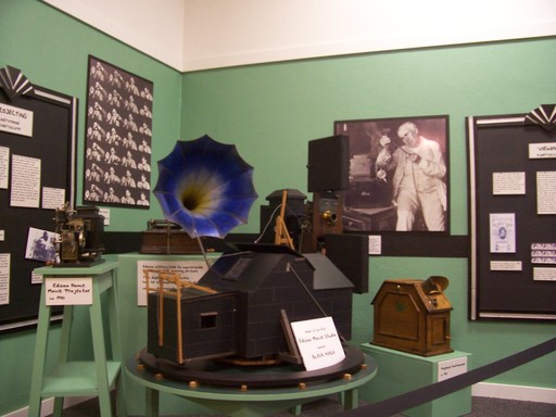 Foreground, from left: a projector, a model of the "black maria" movie studio, a bigger projector with syncronized sound, and a viewer for scenes that moved by flipping postcards. The entire studio rotated to get the sun on the stage.