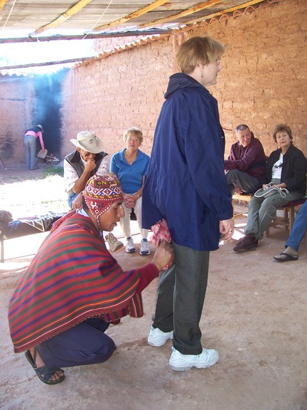 Susan is blessed by the curandero; he glides the packet around her and prays