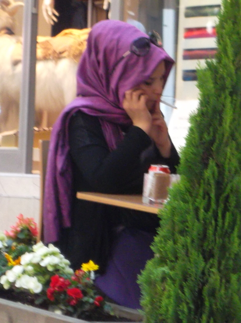  Moderen Moslem Woman in turkey sporting shades, drinking coffee, talking on cell phone, and smoking