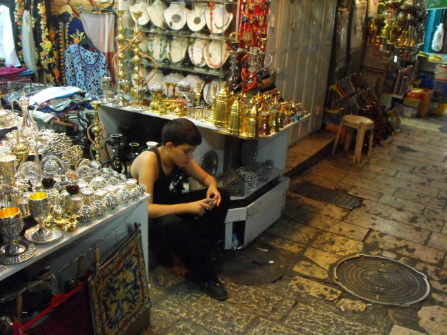  A patient vendor plays a game on his cell phone, Old City, Jerusalem